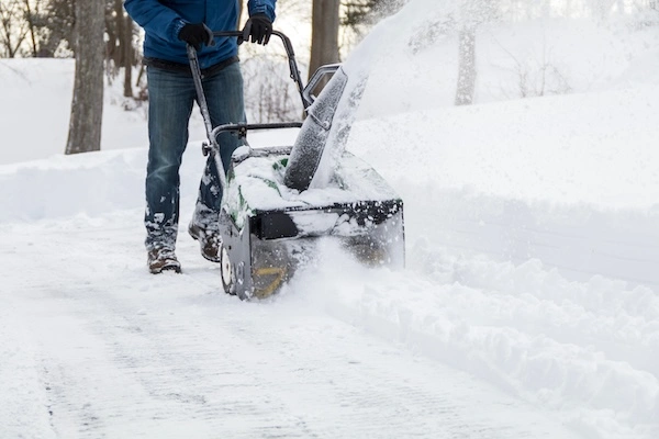 Snow blower clearing a residential driveway after a storm